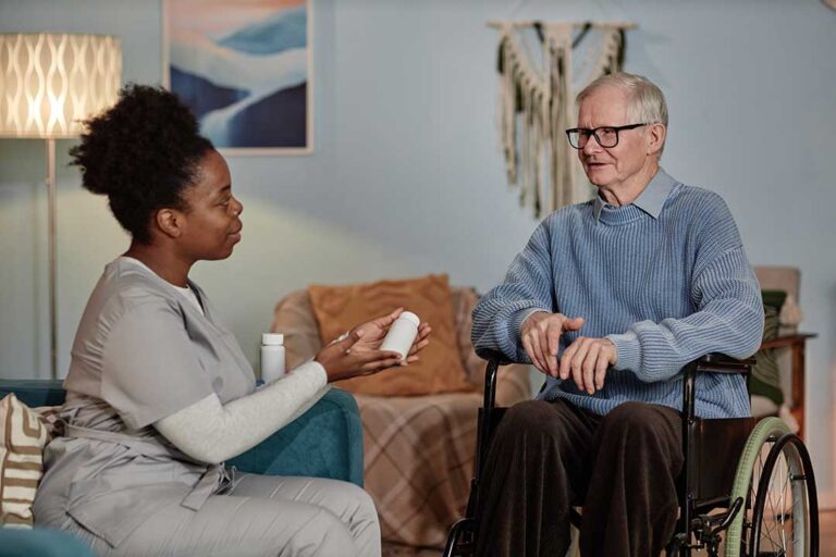 Older adults share conversation at a table in a bright assisted living common room.